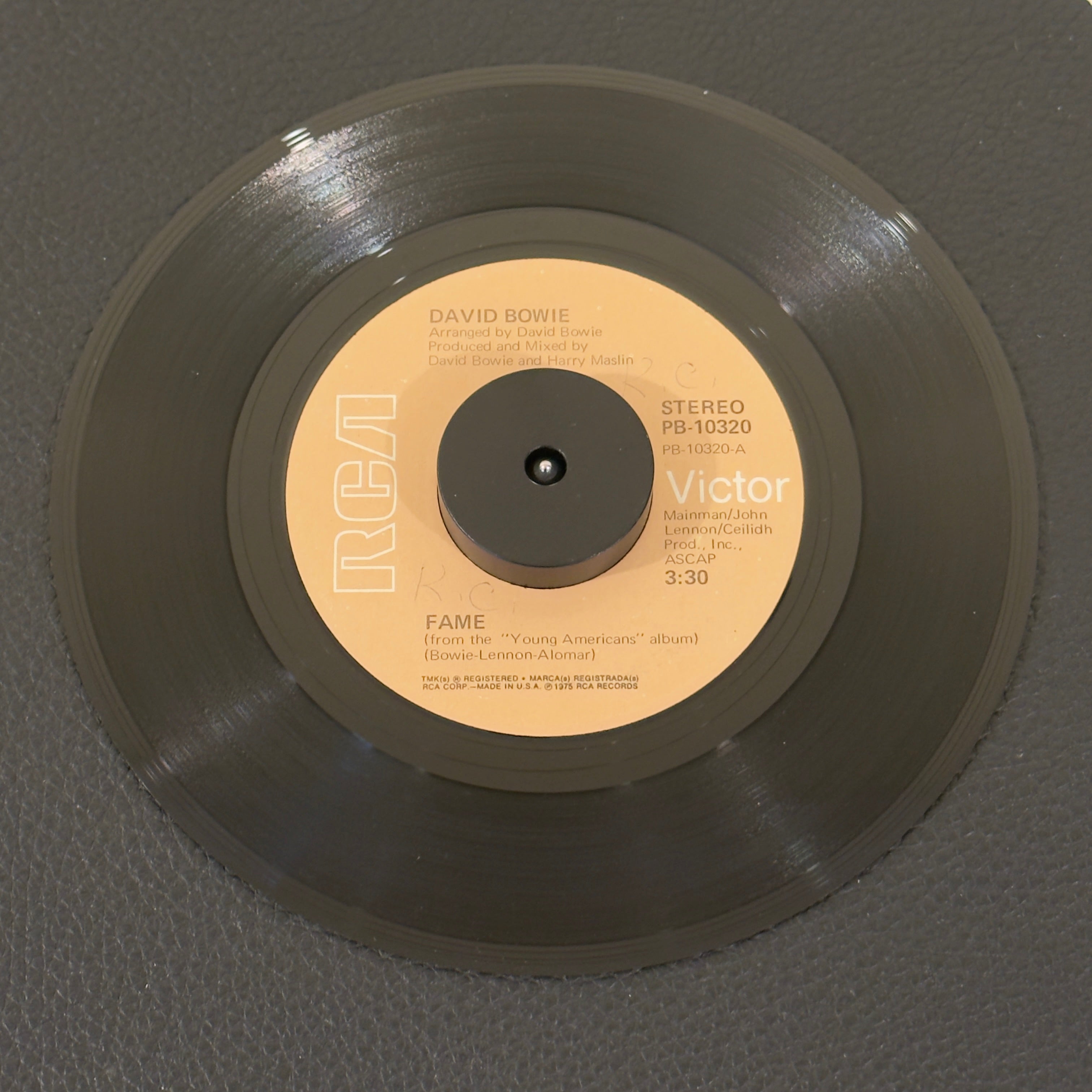 7" vinyl record by Bowie, David featuring "Fame/Right", released on RCA Victor (PB-10320), in VG+ (Very Good Plus) condition, classic analog collectable for turntable playback. Original RCA sleeve included. Writing on label Side A.