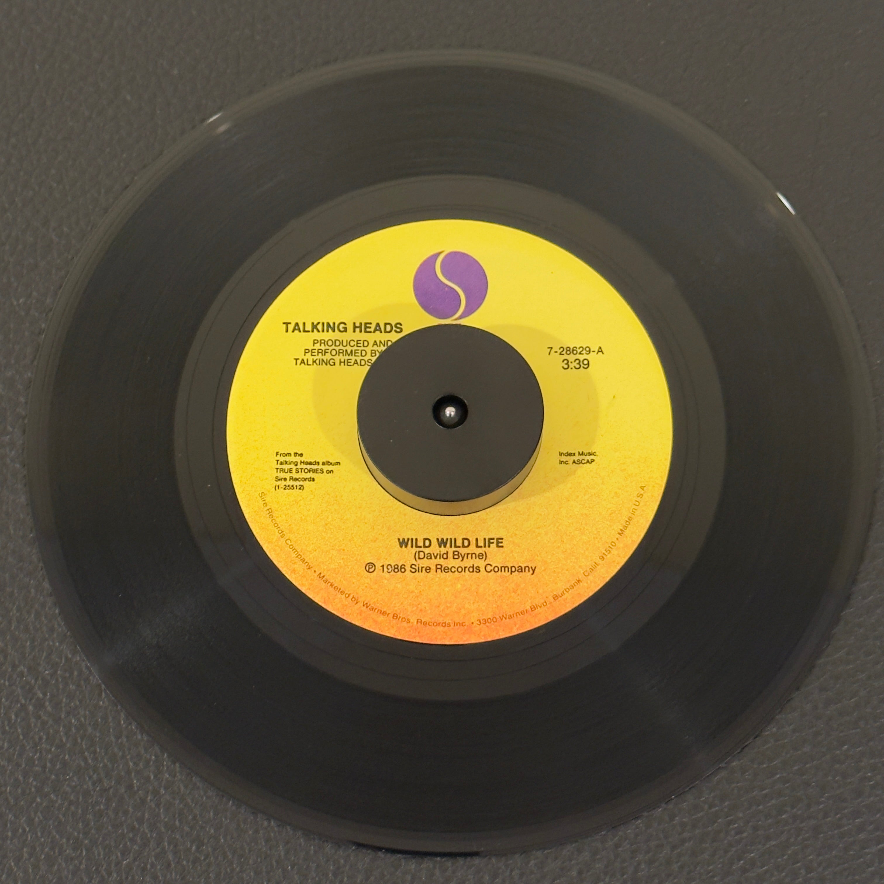 7" vinyl record by Talking Heads featuring "Wild Wild Life/People Like Us (Movie Version)", released on Sire (7-21975), in NM (Near Mint) condition, classic analog collectable for turntable playback. Specialty Pressing. Original Warner Bros. sleeve included. Pic Sleeve not included.